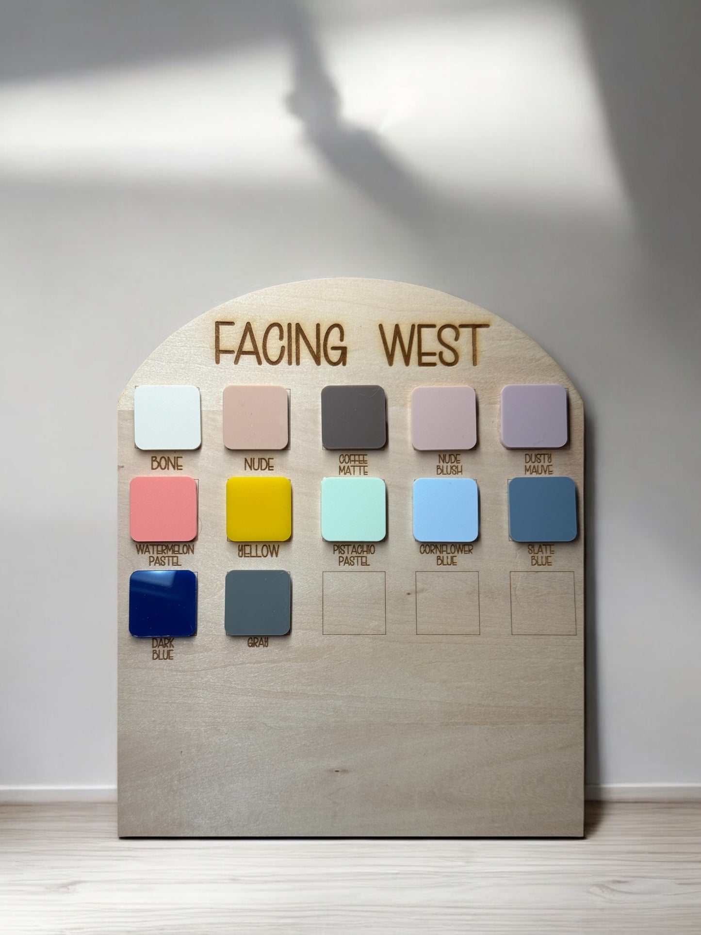 Color palette display board featuring pastel shades like nude, yellow, and blue on a wooden backing.