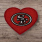 Red heart-shaped patch featuring San Francisco 49ers logo, embroidered fabric for sports fans.